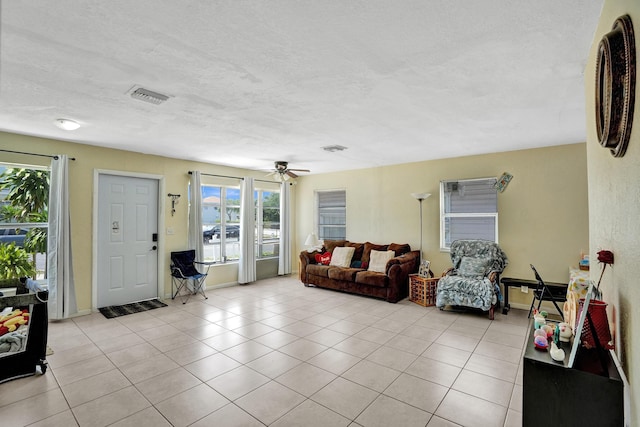 living room featuring a textured ceiling, ceiling fan, and light tile patterned floors