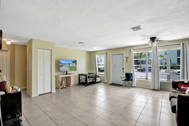 living room featuring ceiling fan, light tile patterned floors, and a textured ceiling