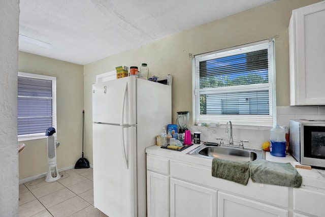 kitchen featuring white cabinetry, light tile patterned flooring, a textured ceiling, white refrigerator, and sink