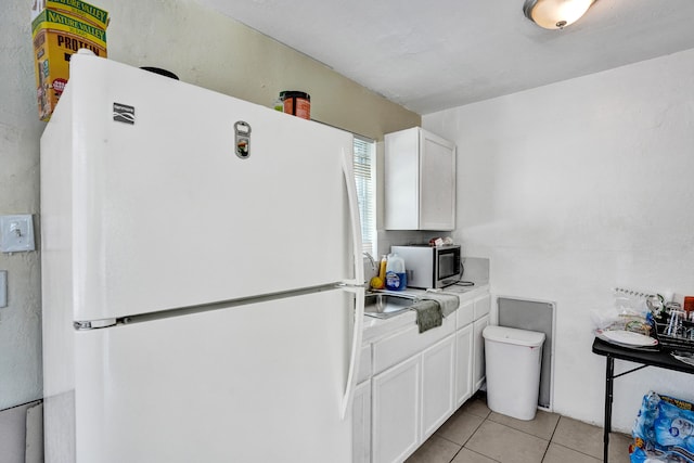 kitchen featuring white fridge, light tile patterned floors, and white cabinets