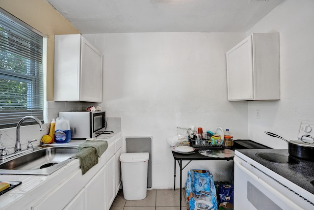 kitchen featuring electric stove, white cabinets, sink, and light tile patterned floors