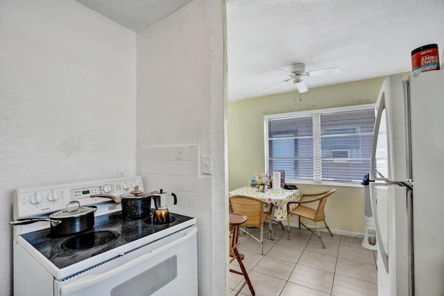 kitchen featuring ceiling fan, light tile patterned floors, tile walls, and white appliances