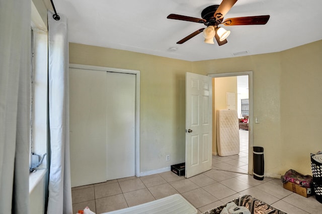 tiled bedroom with ceiling fan and a closet