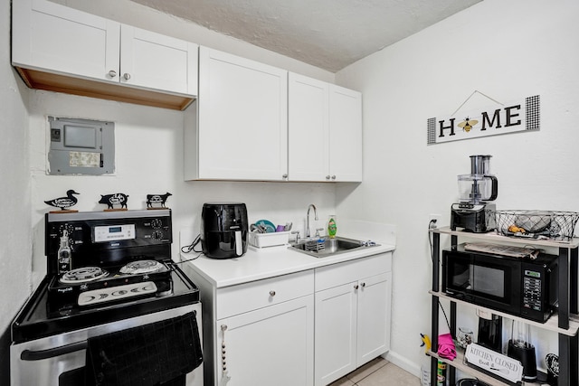 kitchen with light tile patterned floors, white cabinetry, sink, and black appliances