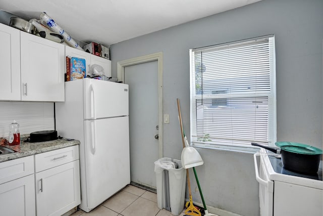 kitchen with white cabinetry, light tile patterned floors, white refrigerator, and a healthy amount of sunlight