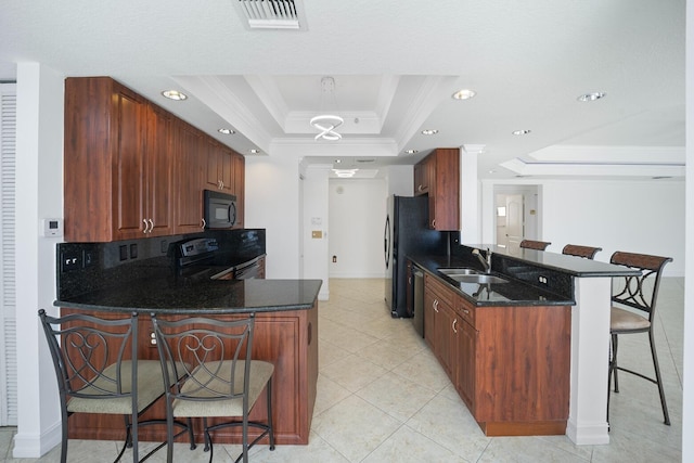 kitchen featuring black appliances, sink, a tray ceiling, kitchen peninsula, and a breakfast bar area