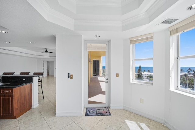 interior space with a breakfast bar, a water view, ceiling fan, and crown molding