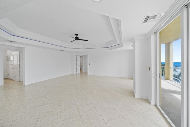 unfurnished room featuring a raised ceiling, ceiling fan, crown molding, a water view, and light tile patterned flooring