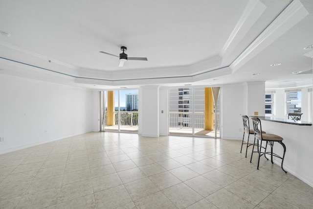 empty room featuring light tile patterned floors, a raised ceiling, ceiling fan, and crown molding