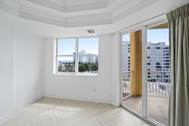 empty room with a raised ceiling, a wealth of natural light, crown molding, and light tile patterned flooring