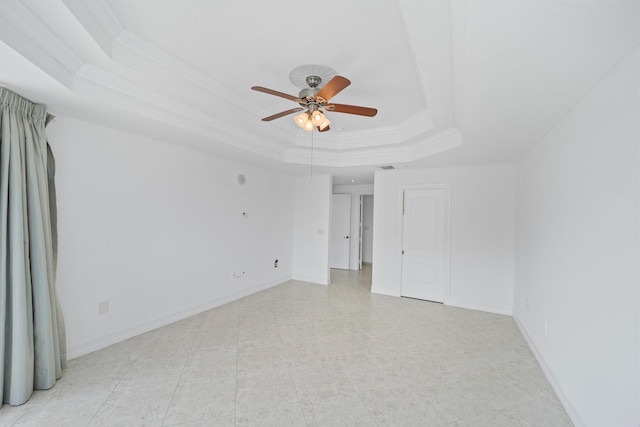 empty room with a raised ceiling, ceiling fan, and ornamental molding