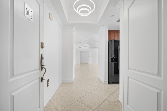 hallway with light tile patterned floors, a tray ceiling, and crown molding