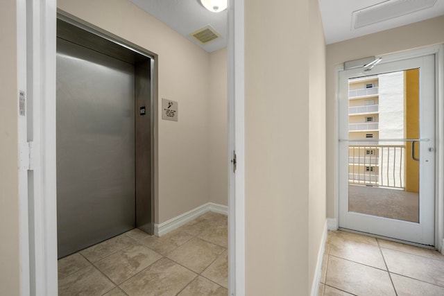 corridor featuring light tile patterned floors and elevator