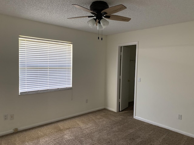 carpeted empty room featuring a textured ceiling and ceiling fan