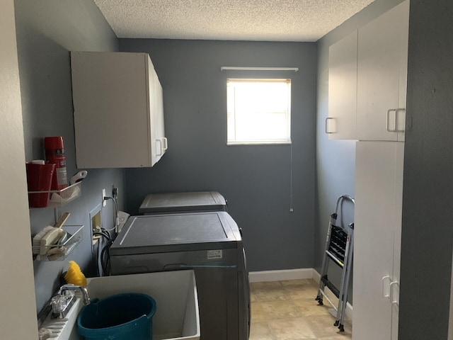 laundry area featuring cabinets, a textured ceiling, washing machine and dryer, and sink