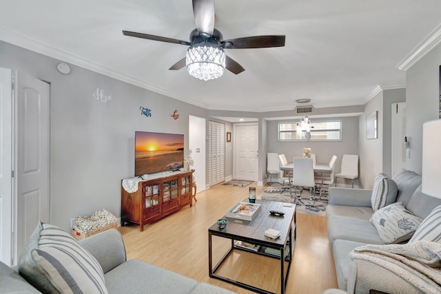 living room with crown molding, ceiling fan, and light wood-type flooring