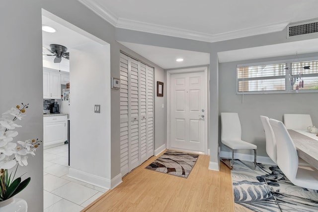 foyer entrance with ceiling fan, crown molding, and light hardwood / wood-style floors