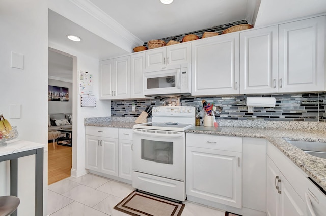 kitchen with light stone countertops, white cabinets, white appliances, light tile patterned floors, and ornamental molding