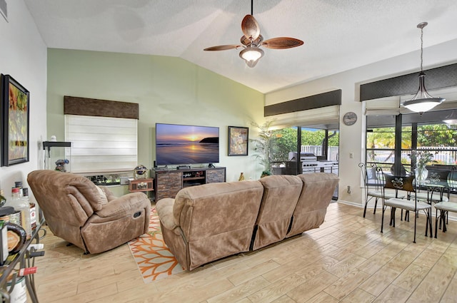 living room featuring a textured ceiling, light wood-type flooring, ceiling fan, and lofted ceiling