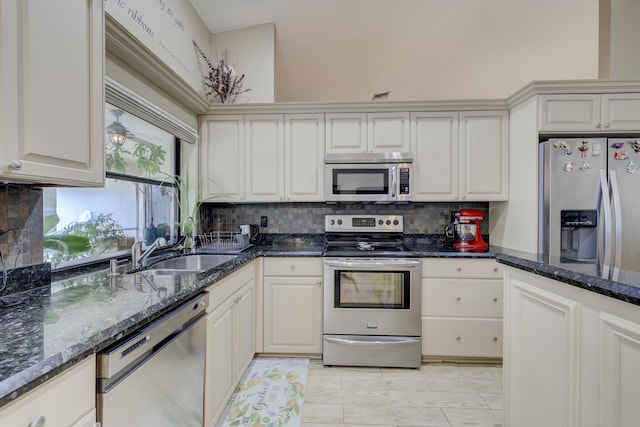 kitchen featuring white cabinetry, sink, backsplash, dark stone countertops, and appliances with stainless steel finishes