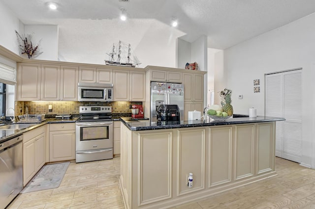 kitchen featuring sink, stainless steel appliances, dark stone countertops, a textured ceiling, and a kitchen island