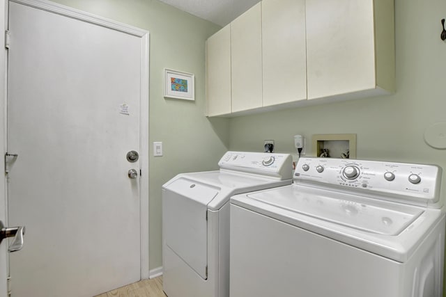 laundry room with washer and dryer, light hardwood / wood-style floors, cabinets, and a textured ceiling