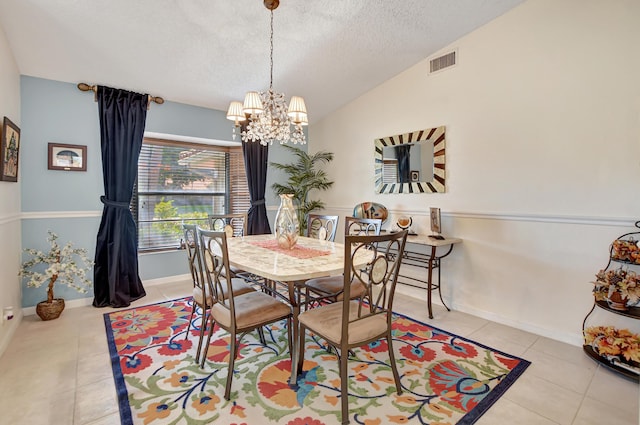 tiled dining space with a textured ceiling, lofted ceiling, and a notable chandelier