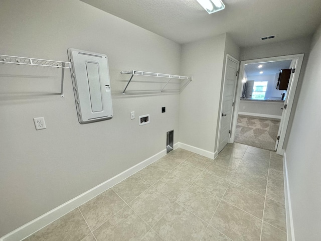 clothes washing area featuring electric dryer hookup, electric panel, washer hookup, light tile patterned floors, and a textured ceiling