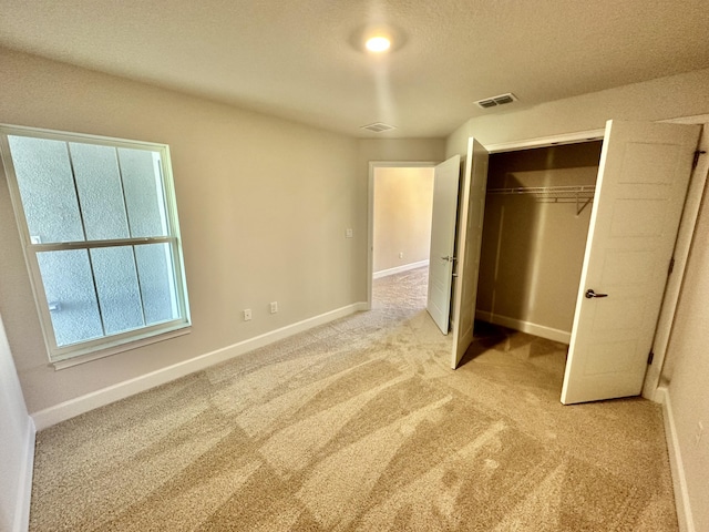 unfurnished bedroom with a textured ceiling, light carpet, and a closet