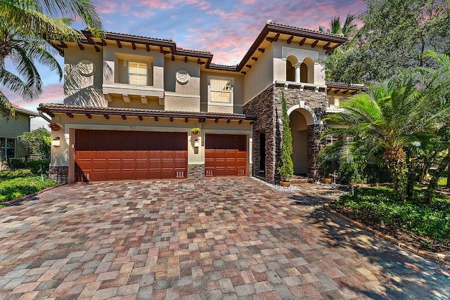 mediterranean / spanish-style house featuring stone siding and decorative driveway