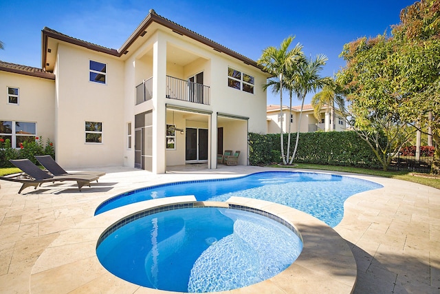 exterior space with stucco siding, a pool with connected hot tub, a patio area, fence, and a balcony