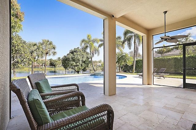 sunroom / solarium with a water view, ceiling fan, and a patio area