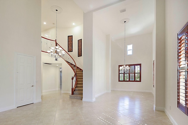 entryway with visible vents, a high ceiling, light tile patterned flooring, a chandelier, and stairs