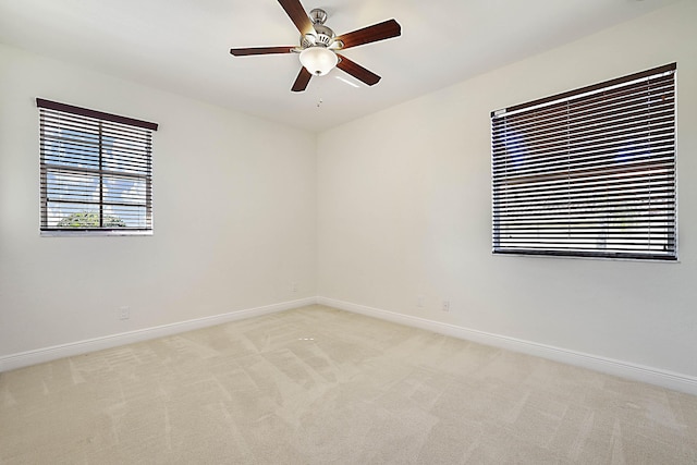 spare room with ceiling fan and light colored carpet