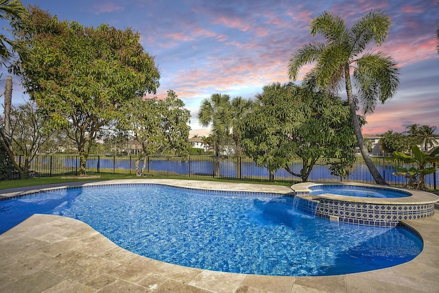 pool at dusk with a patio, a fenced backyard, and a pool with connected hot tub