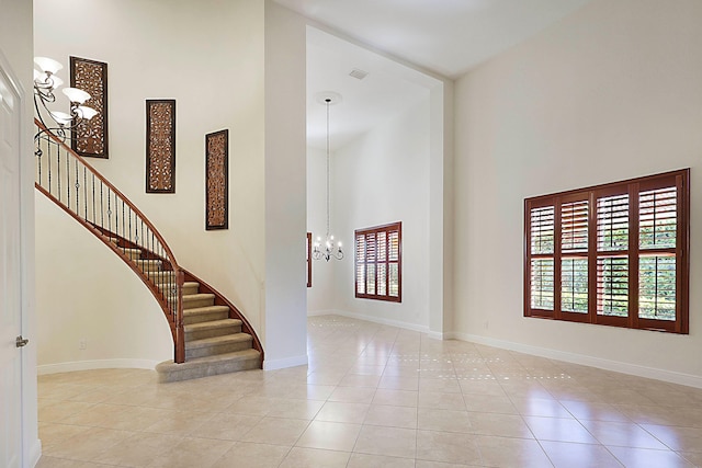 entryway featuring a notable chandelier, a towering ceiling, and light tile patterned floors