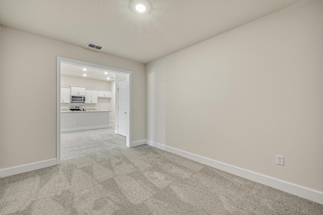 carpeted spare room with a textured ceiling