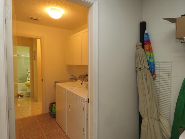 laundry room with cabinets, a textured ceiling, sink, light tile patterned floors, and washing machine and clothes dryer