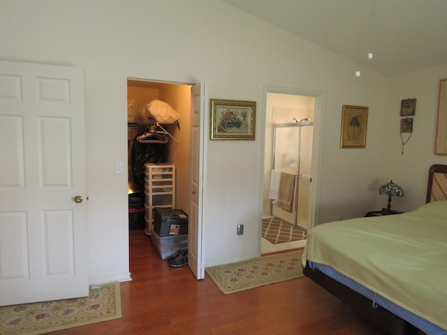 bedroom featuring lofted ceiling, ensuite bathroom, a walk in closet, dark hardwood / wood-style floors, and a closet