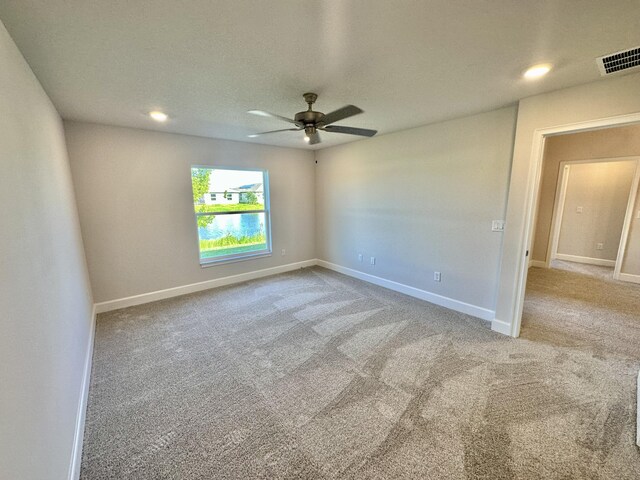 unfurnished bedroom featuring ceiling fan, a walk in closet, and light carpet