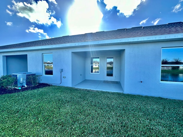 back of property with a yard, a patio, and central AC