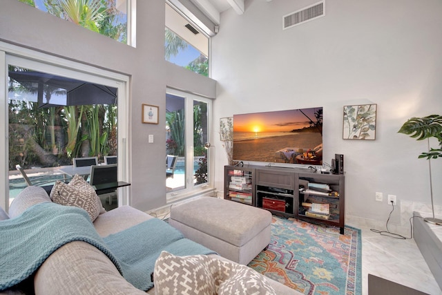 living room featuring beamed ceiling and a high ceiling