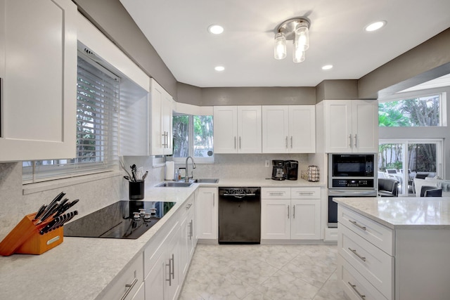 kitchen with light stone countertops, sink, decorative backsplash, white cabinets, and black appliances