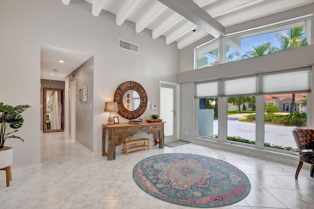 foyer entrance featuring beam ceiling, light tile patterned floors, and high vaulted ceiling