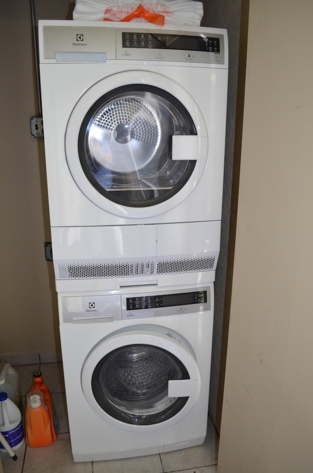 clothes washing area featuring stacked washer / drying machine and light tile patterned flooring