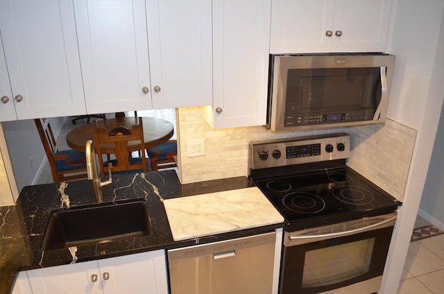 kitchen with white cabinets, appliances with stainless steel finishes, and tasteful backsplash