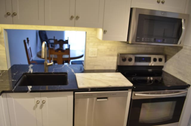 kitchen with white cabinets, backsplash, sink, and stainless steel appliances