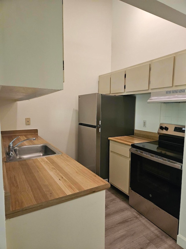 kitchen with sink, light hardwood / wood-style flooring, stainless steel appliances, decorative backsplash, and cream cabinetry