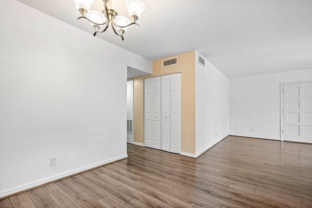 additional living space with a chandelier and hardwood / wood-style floors