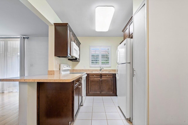 kitchen with sink, kitchen peninsula, white appliances, a kitchen bar, and light tile patterned flooring